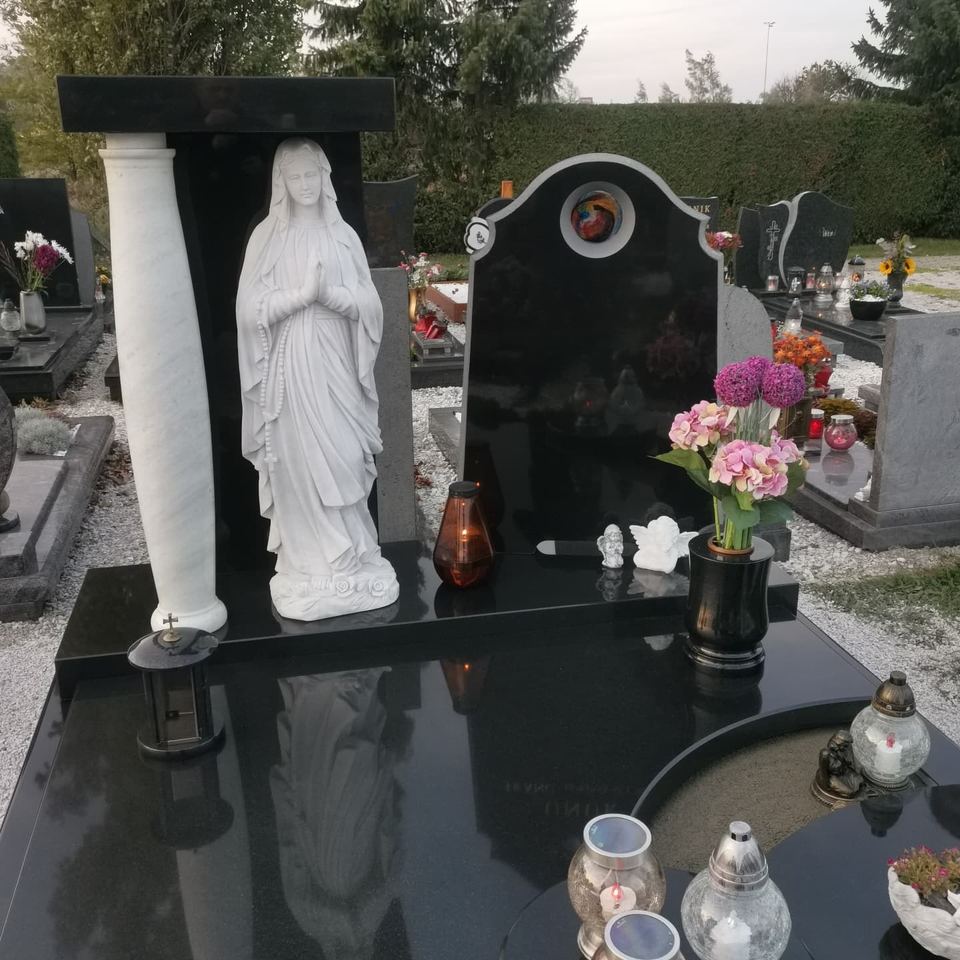 Grab aus schwarzem Granit mit weißer Säule und Marienstatue