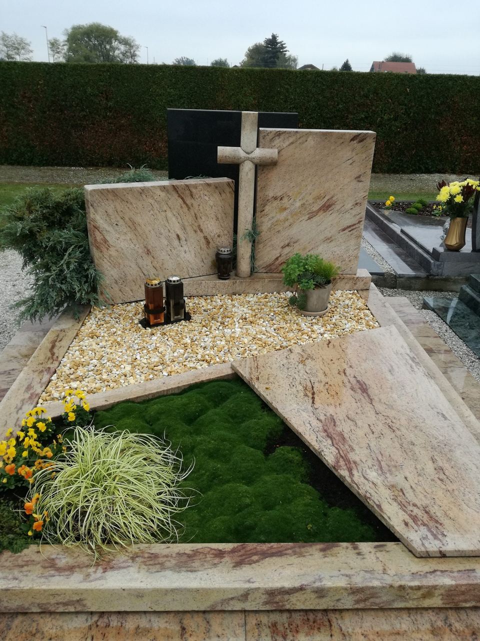 Grab aus hellem beigem Granit mit Kreuz und Rasenfläche