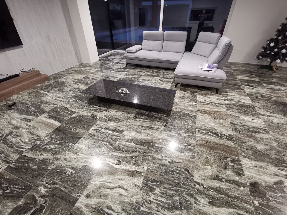 Couchtisch aus dunklem Stein auf einem Boden aus grauem Granit
