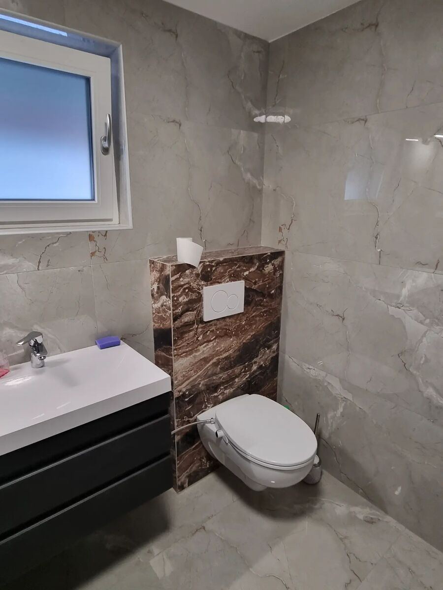 Bad mit weißem Marmor und brauner Feinsteinzeugverkleidung am WC