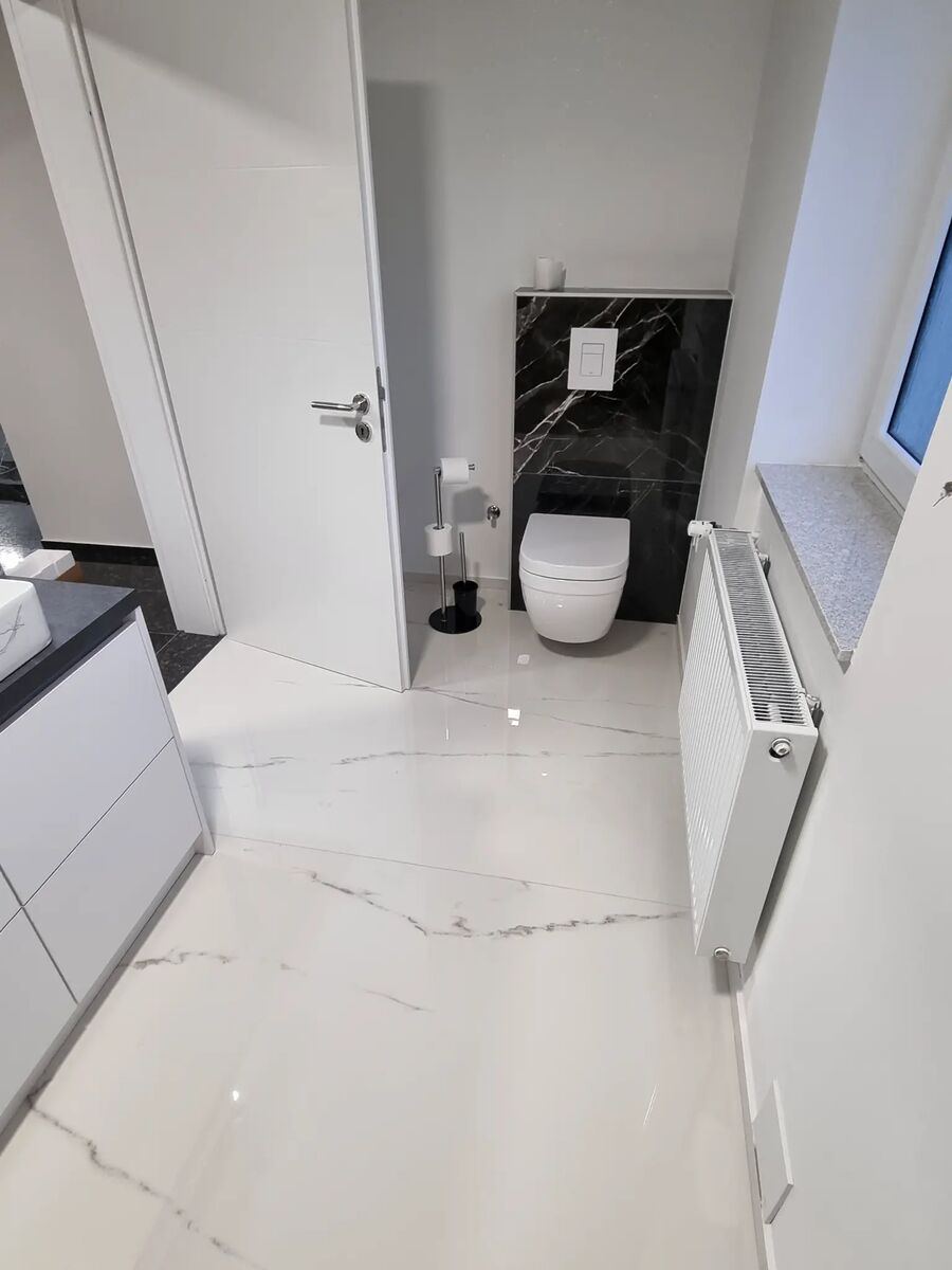 Bad mit weißen Marmorböden Calacatta und schwarzer Feinsteinzeugverkleidung am WC