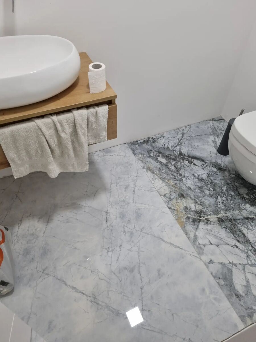Bad mit weißen Marmorböden und Waschtisch aus Holz