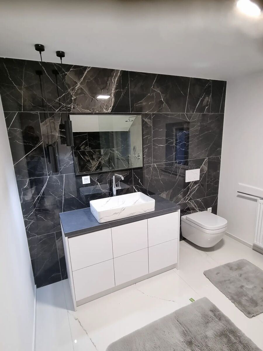 Bad mit schwarzer Wandverkleidung aus Feinsteinzeug und weißem Waschbecken