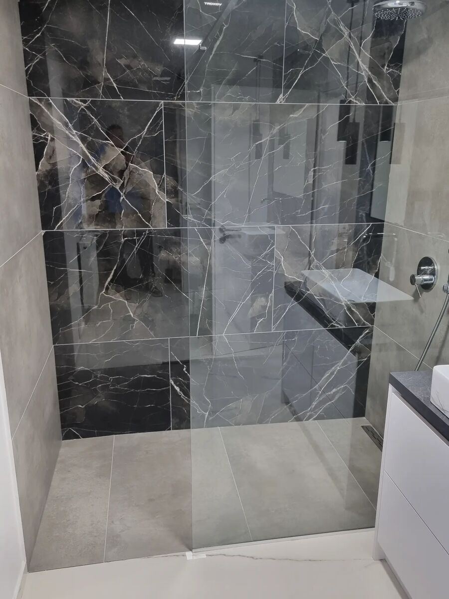 Bad mit schwarzer Dusche aus Feinsteinzeug und weißer Wandverkleidung