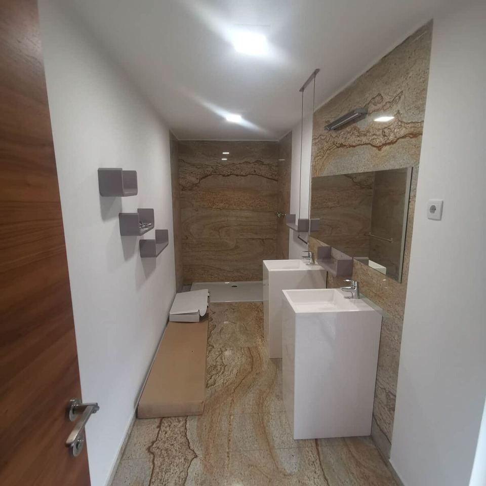 Bad mit Wandverkleidung aus Granit und weißen Waschbecken