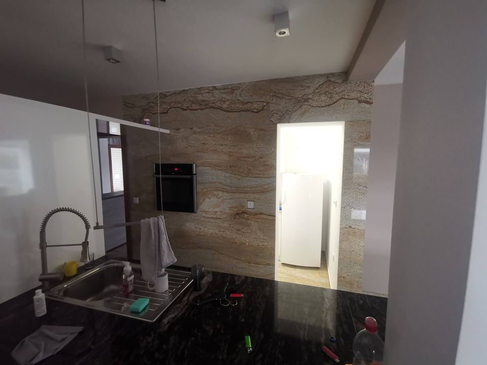 Küche mit Arbeitsplatte aus dunklem Granit und Wand aus gelbbraunem Stein