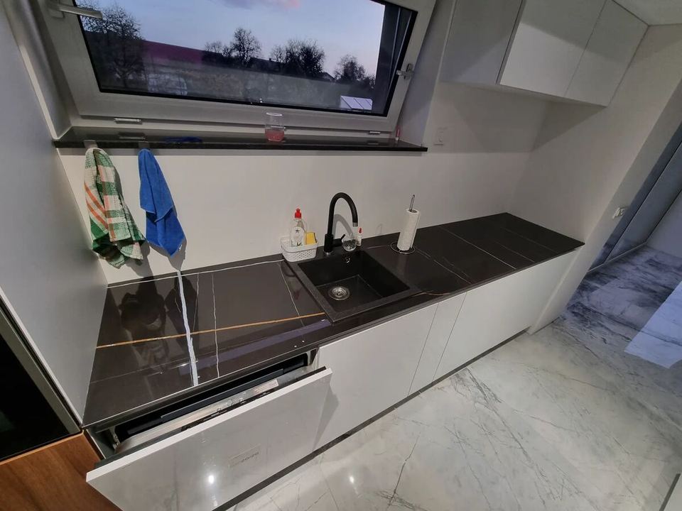 Küchenarbeitsplatte aus schwarzem Granit mit weißer Verkleidung aus Feinsteinzeug