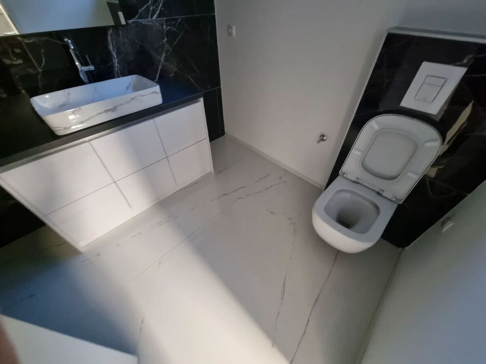 Minimalistisches Bad mit schwarzer Verkleidung aus Feinsteinzeug und weißen Böden