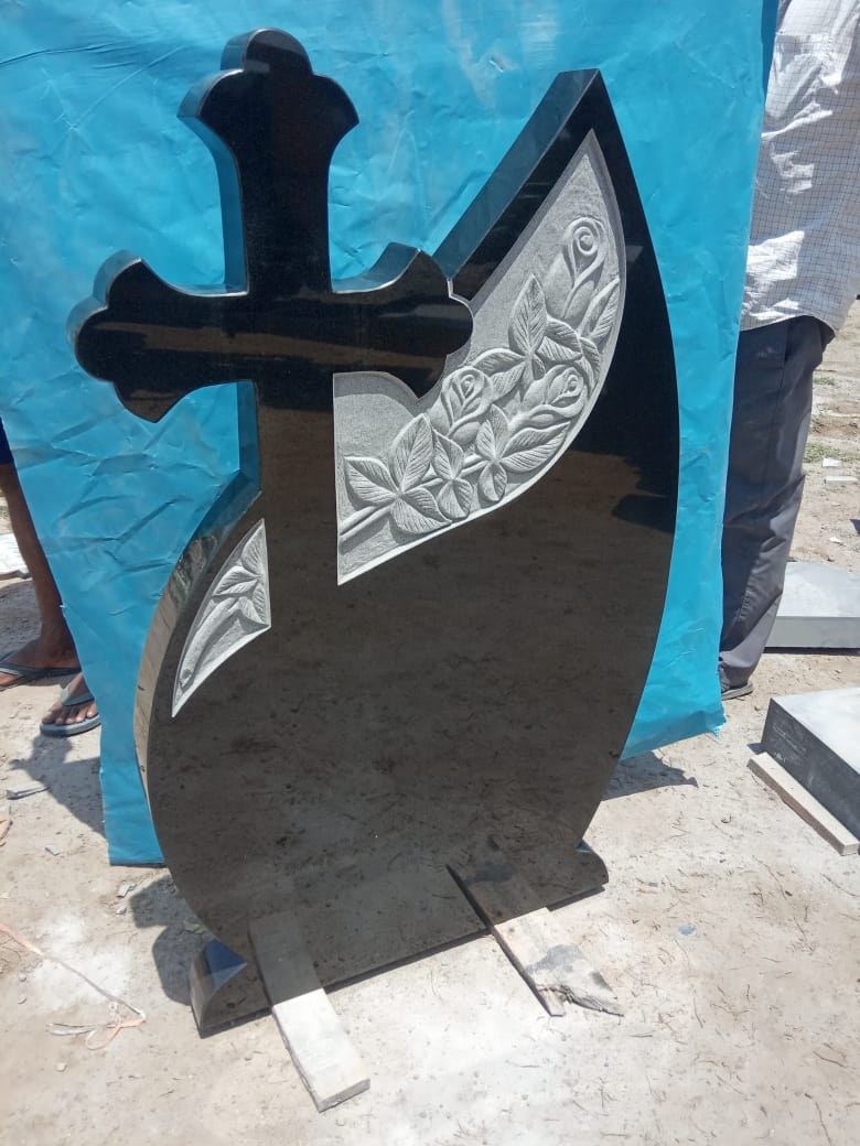 Grabstein aus schwarzem Granit mit Kreuz und eingemeißelter Lilie