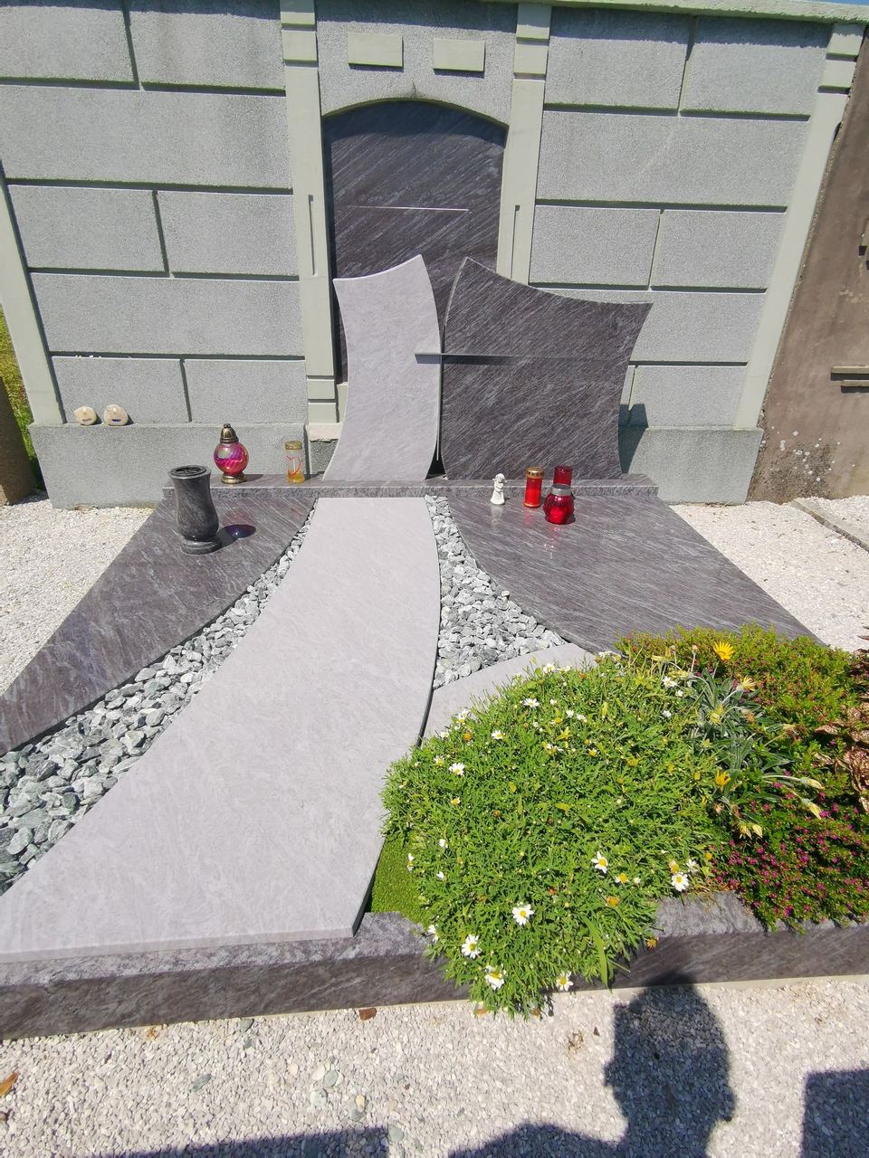 Modernes Grab an der Mauer mit Grabstein aus grauem Granit