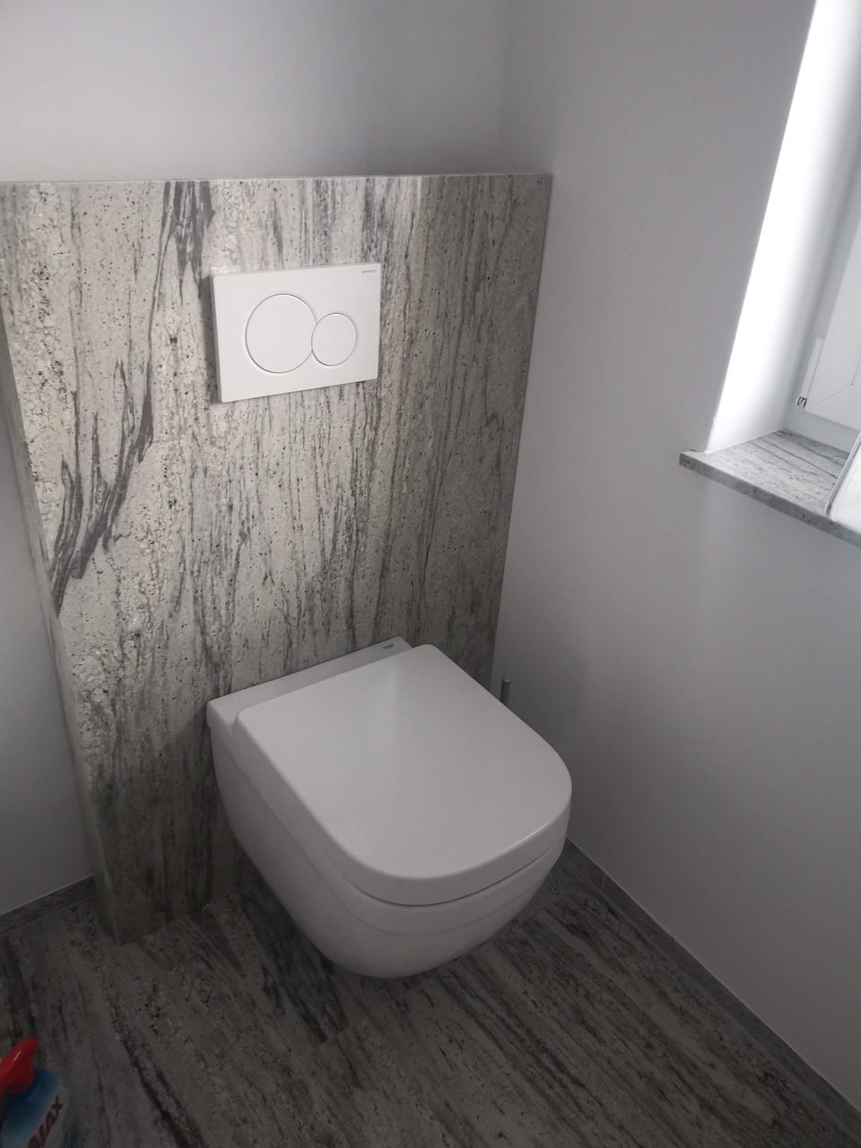 Wandverkleidung hinter der Toilette aus grauem Granit