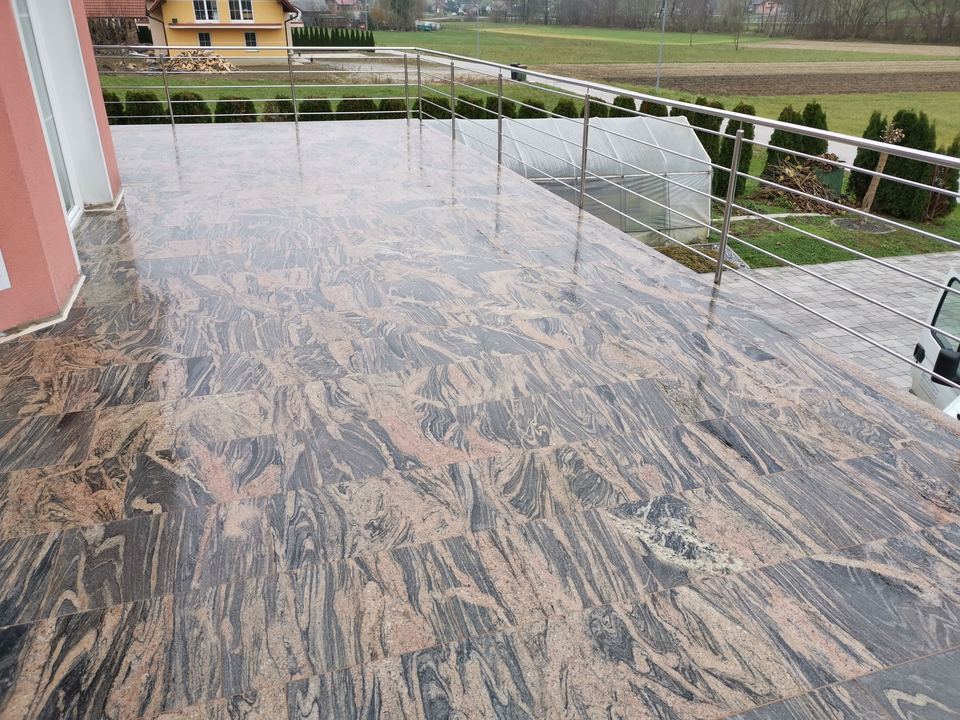 Terrasse mit Granitbelag mit Wellenmuster und Metallgeländer