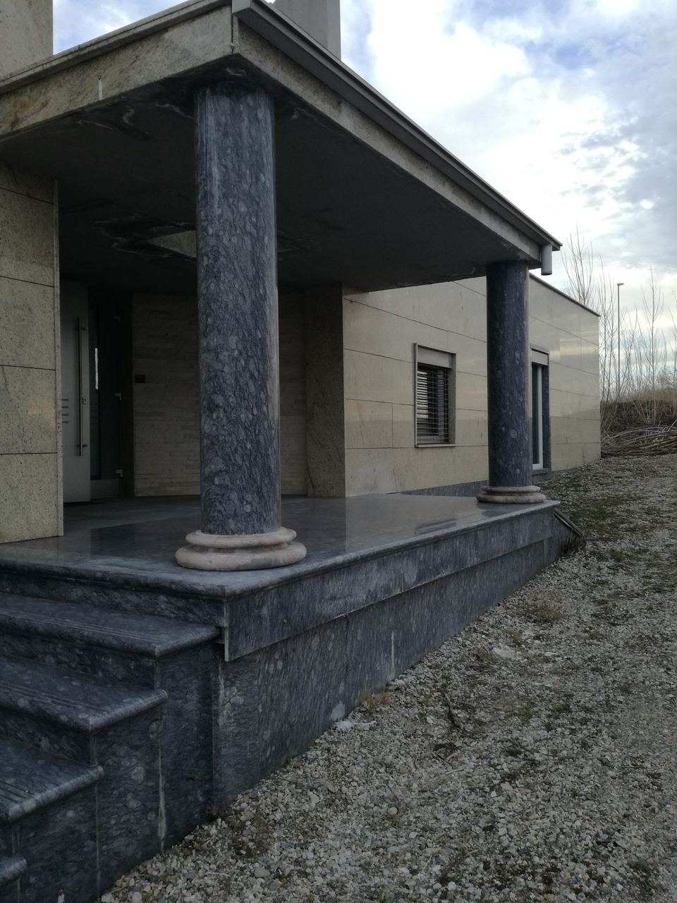 Eingang mit Säulen und Treppe aus dunklem Granit